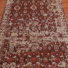 a large brown and white rug on the floor with wooden floors in front of it