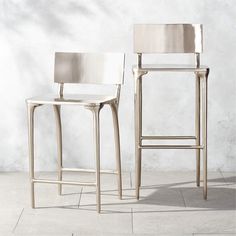 two white chairs sitting next to each other on top of a tile floor in front of a wall