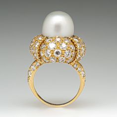 This magnificent cocktail ring is centered with one (1), post set, cultured South Sea pearl. The pearl tops a domed setting is bead set sixty-four (64), bead set, round brilliant cut diamonds. The ring has a split shank design and is accented with seven (7), bead set, round brilliant cut diamonds on each side. The ring measures 21.7mm at the top, rises 18.6mm above the finger, tapering to 2.4mm wide and 1.1mm thick at the base of the shank. The ring is currently size 7. Elegant White Domed Rings, Elegant White Domed Jewelry, Luxury Oval Pearl Ring, Elegant Dome Ring With Cabochon For Wedding, Luxury Domed Jewelry For Formal Occasions, Elegant White Oval Dome Ring, Classic Cabochon Pearl Ring For Formal Occasions, Luxury Cabochon Pearl Ring For Wedding, Classic Cabochon Dome Ring For Wedding