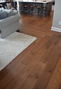 a living room with hard wood floors and white rugs on the hardwood flooring