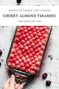 a person holding a container filled with cherries and the words cherry almond triramsu