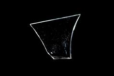 a glass vase sitting on top of a black table next to a white object in the dark