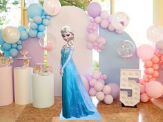 there is a frozen princess standing in front of balloons and decorations on the wall behind her