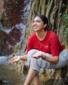 a woman is sitting in the water near a tree