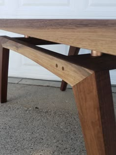 a wooden bench sitting on top of a cement floor next to a white garage door