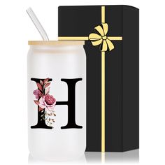 a glass jar with the letter h on it next to a gift box and a straw