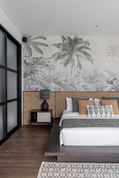 a bedroom with a large bed and palm trees painted on the wall behind it,