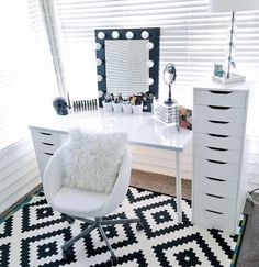 a white chair sitting in front of a mirror on top of a dresser next to a window