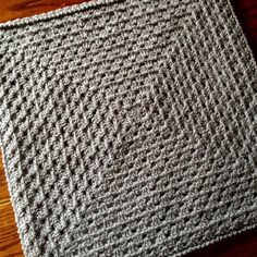 a crocheted square sitting on top of a wooden floor