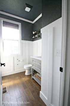 a white bathroom with wood floors and gray walls