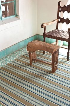 an old wooden bench sitting on top of a rug next to a chair and window