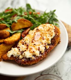 a white plate topped with fried chicken and french fries next to a side of salad