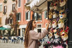 a woman standing next to a pole with lots of masks on it