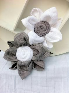 two towels are placed on top of each other with flowers in the middle and white petals at the bottom