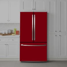 a red refrigerator in a kitchen next to white cabinets and cupboards with silver handles