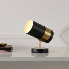 a black and gold desk lamp on top of a white table next to a stack of books