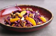 a bowl filled with purple cabbage and oranges