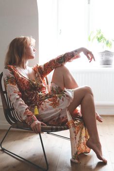 a woman is sitting in a chair with her legs crossed and looking out the window