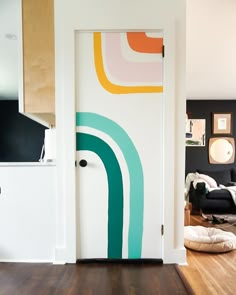 an open door in a living room with wood flooring and artwork on the wall