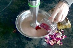 a person pouring something into a glass on top of a plate with food in it