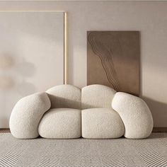 a white couch sitting on top of a rug next to a wooden framed art piece