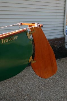 a green and brown boat sitting next to a white house