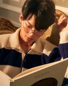 a young man wearing glasses reading a book