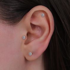 a close up of a person's ear with three diamond studs on it