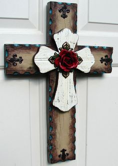 a wooden cross with a red rose on it is hanging from the front door,