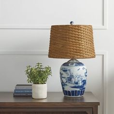 a blue and white vase sitting on top of a wooden table next to a lamp