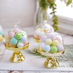 there are three glass domes with candy in them on the table next to each other