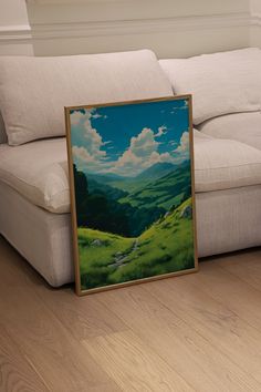 a painting sitting on top of a wooden floor next to a white couch