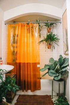 an orange shower curtain in a bathroom with potted plants