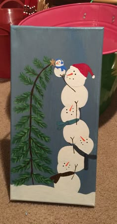 a snowman painting on a canvas in front of a red bowl with other items