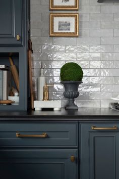 a kitchen with blue cabinets and white tile backsplashing, gold trimmings