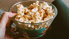 a person holding a bowl of popcorn in their hand