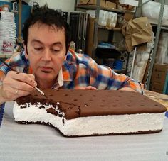 a man is eating an ice cream cake with chocolate frosting and sprinkles