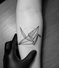 a black and white photo of a person's arm with an origami tattoo on it