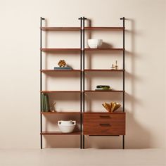 an empty shelf with some books and other items on it, against a beige wall