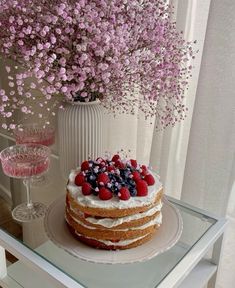 a cake sitting on top of a glass table next to a vase filled with flowers