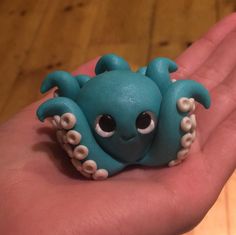 a small blue toy octopus sitting on top of someone's hand