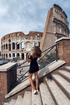 a woman is standing on some stairs in front of the colossion