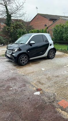 a small black and white car parked in a parking lot