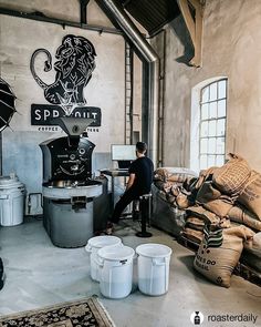 a man sitting at a table in front of a coffee pot and some buckets