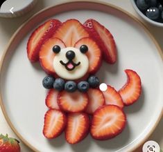 a white plate topped with strawberries and a dog shaped cookie on top of it