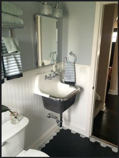 a white sink sitting under a bathroom mirror next to a black and white floor rug