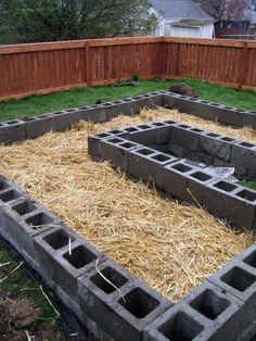 the garden is made out of cinder blocks and straw bales, with grass growing in between them