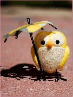 a stuffed owl holding an umbrella on the ground