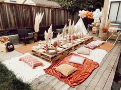 a wooden table topped with lots of white and orange decorations next to a fenced in area