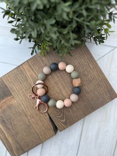 a wooden board with a bracelet on it next to a potted plant